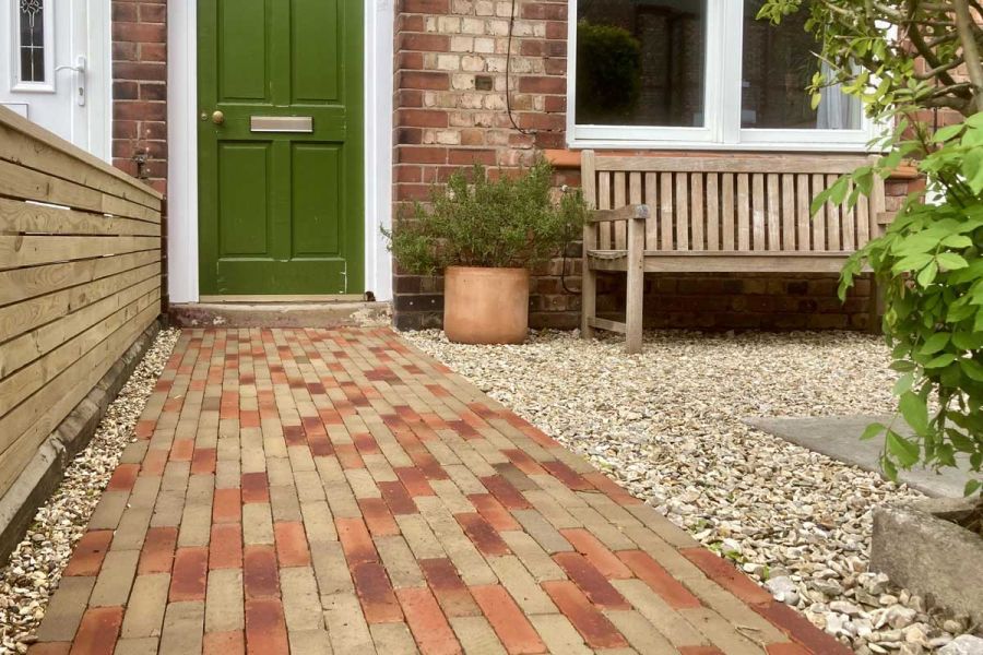Westminster and Seville Clay Paving path to front door, by gravelled and paved garden with wooden bench and low slatted fence.