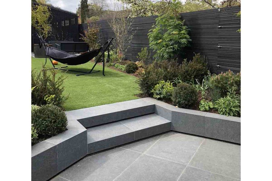 2 steps rise between beds from patio in Basalt porcelain paving to lawn. Design by Jen Berry. Built by Lanwarne Landscapes.