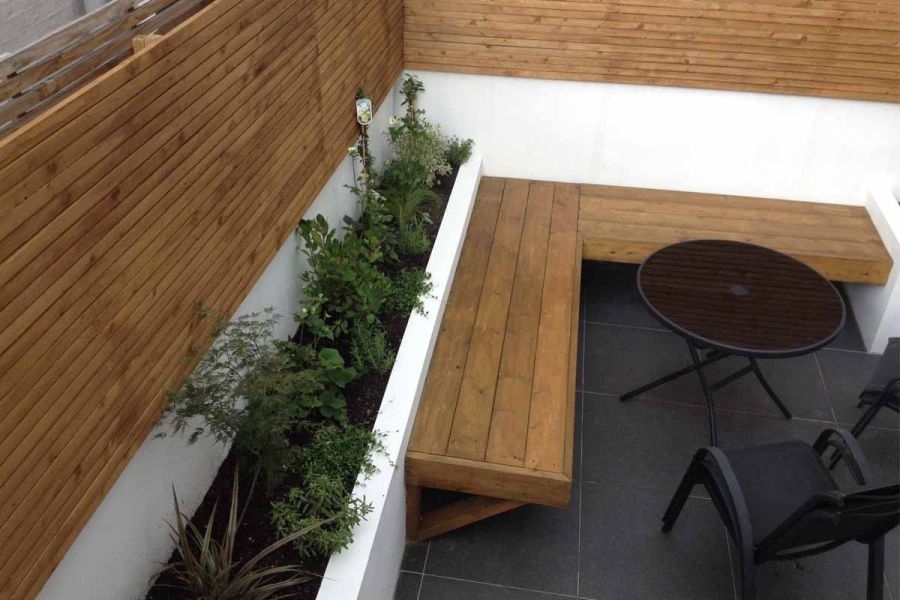 Small courtyard with cedar slatted fence panels and garden benches, featuring a metal bistro set ideal for relaxing outdoors.