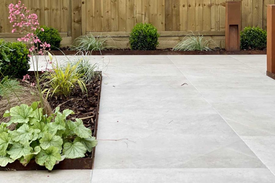 Ash Beige Porcelain patio adjoined to Corten Steel edged planted flower beds with a layer of weed supressing bark mulch.