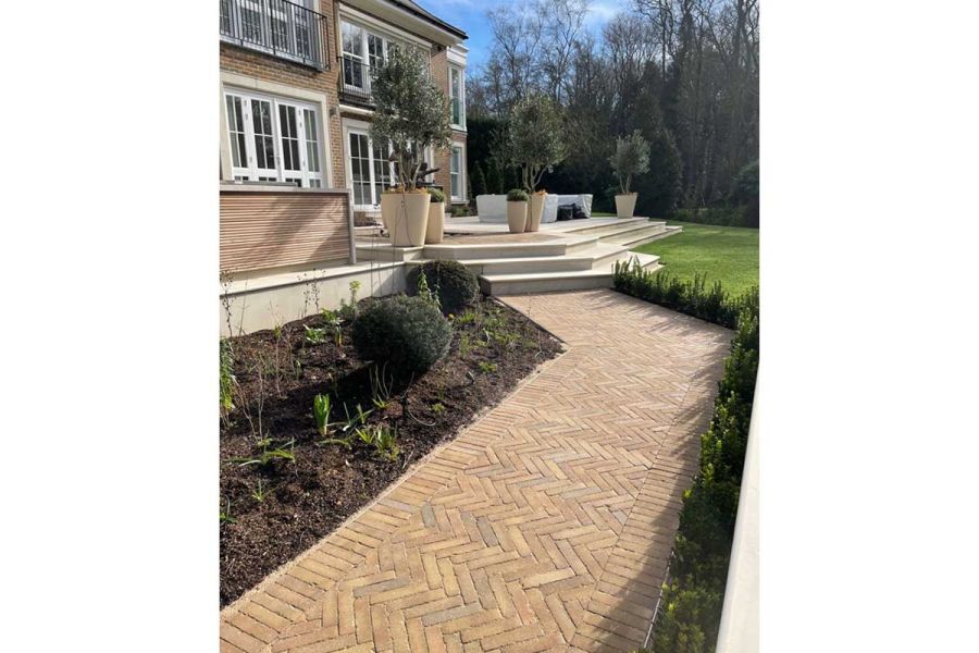 Clay paver path leads to 3 angled Beige Smooth Sandstone bullnose steps rising to patio with large pots. Designed by Kate Gould.