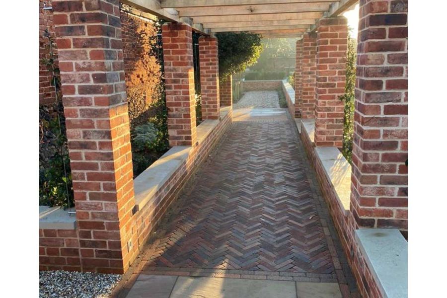 Romsey Antique Clay Pavers laid herringbone in wide path under colonnade with brick pillars and low walls with coping stones.