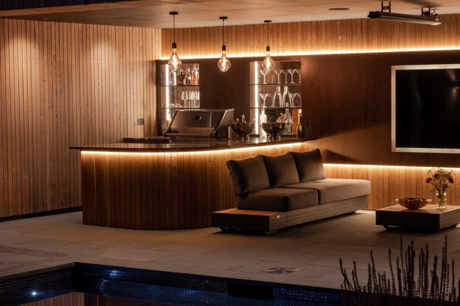 Curved bar and 3-seater sofa in illuminated interior paved with Black granite slabs.
