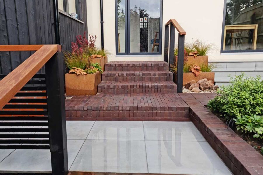 porcelain- paved area with step up to bolzano clay paving pubs and edging. Three steps up to glass door. Design by Jane Houghton.