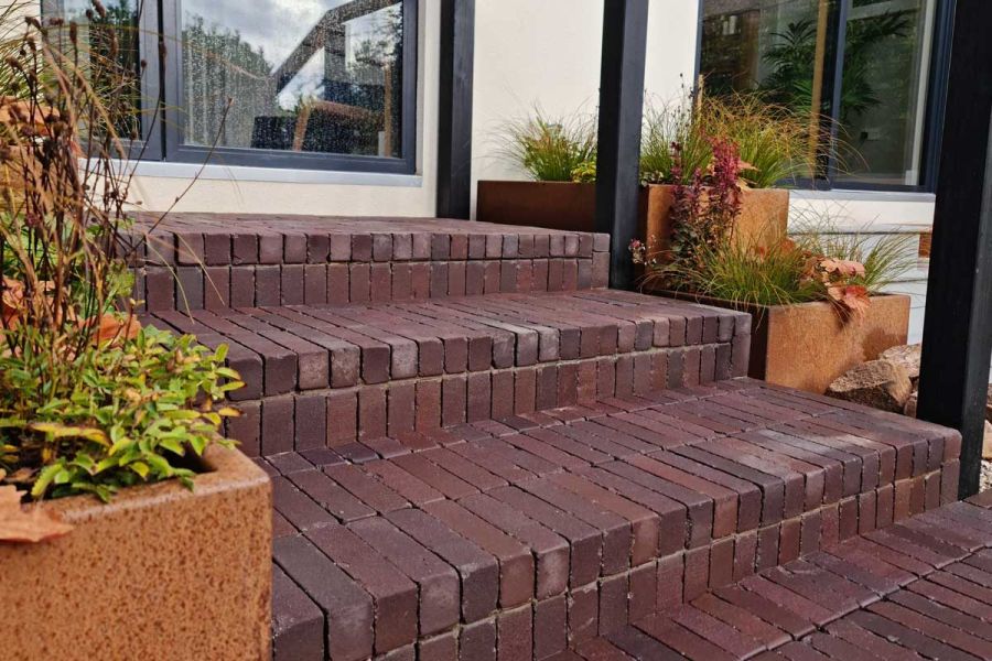 Near view of Bolzano clay paver steps rising to glass door between planters. Design by Jane Houghton. Built by Landigo Ltd.