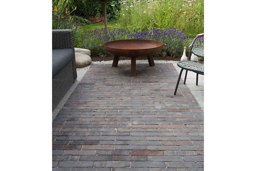 3-legged metal fire bowl on Ancona clay paving with lavender hedge behind. Design by Bramley Apple. Built by Waterfeatures Ltd.