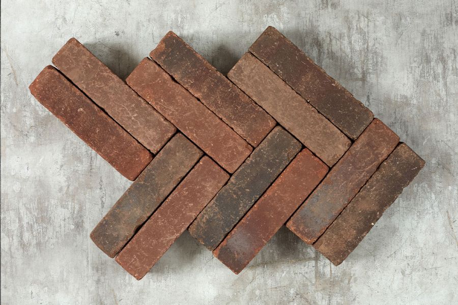 12 Antique Red brick pavers laid in a double herringbone pattern against a pale background, showing bricks’ tones of red and grey. 