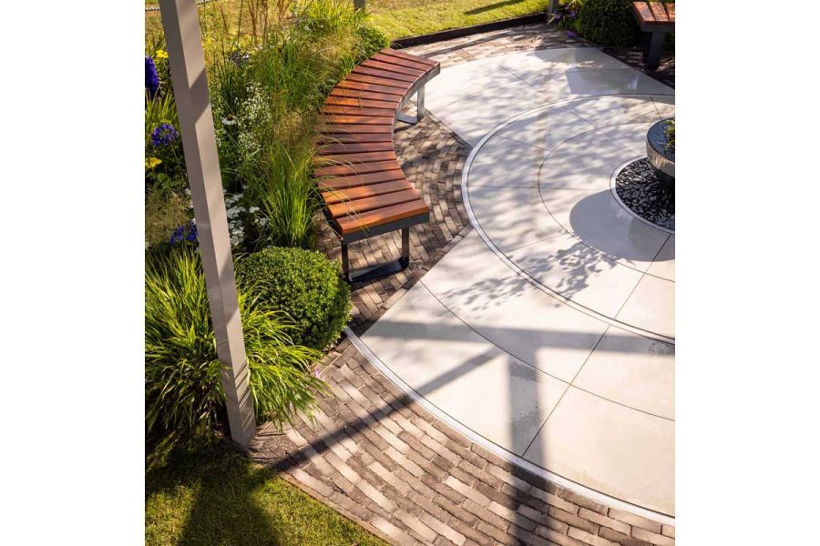 Round water feature in centre of bespoke paving circle edged with 11 courses of Silver Grey Multi clay pavers. Design by Lynn Cordall.