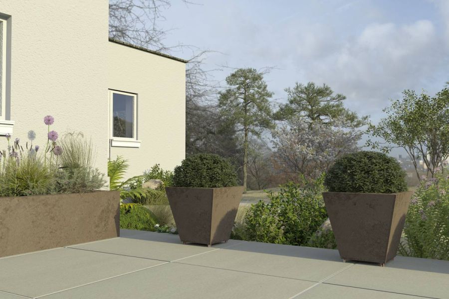 Patio terrace made with Yard porcelain paving featuring corten steel planters and looking across a large country garden.
