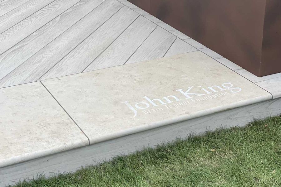 Jura Beige bullnose limestone step tread engraved with John King logo edges pale decking in RHS Hampton Court show garden 2022.