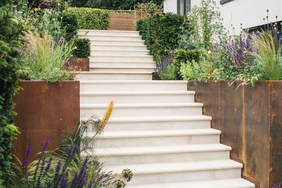 Flight of Beige Smooth Sandstone Bullnose step treads between tall corten steel planters and hedging. Built by Artisan Landscapes.