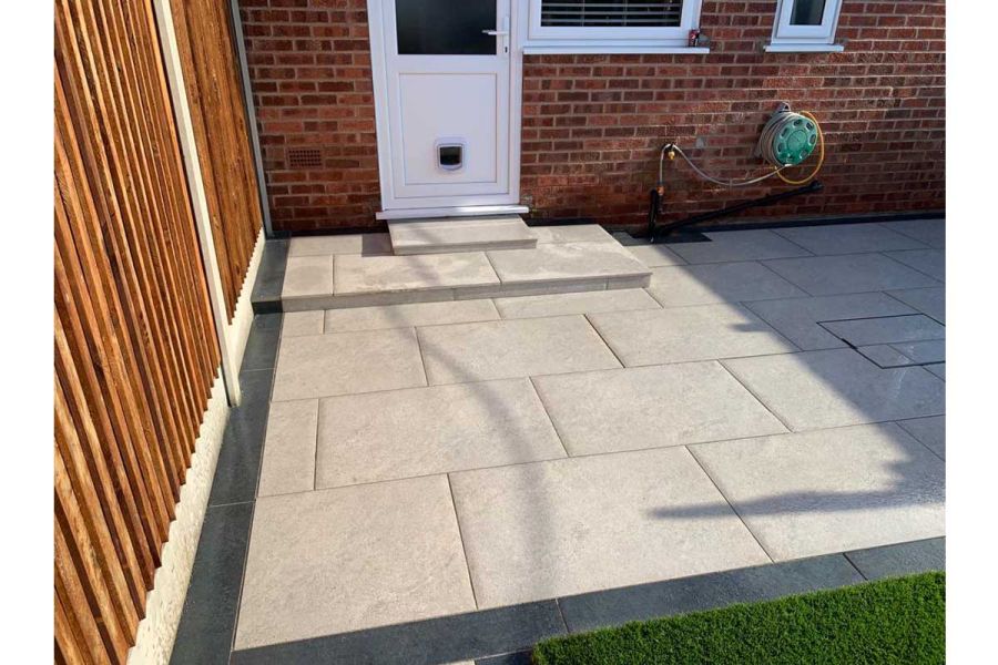 2 shallow steps outside back door down to light grey patio with edge of Charcoal porcelain planks. Built by C and C Agricultural.