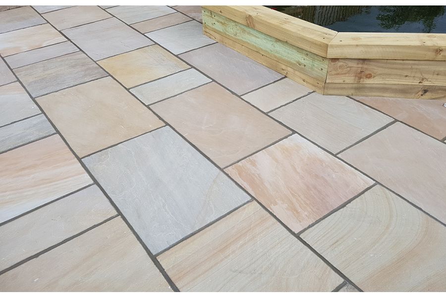 Camel Dust Indian sandstone project pack paving slabs laid in courses, showing range of pastel colours with dark pointing.