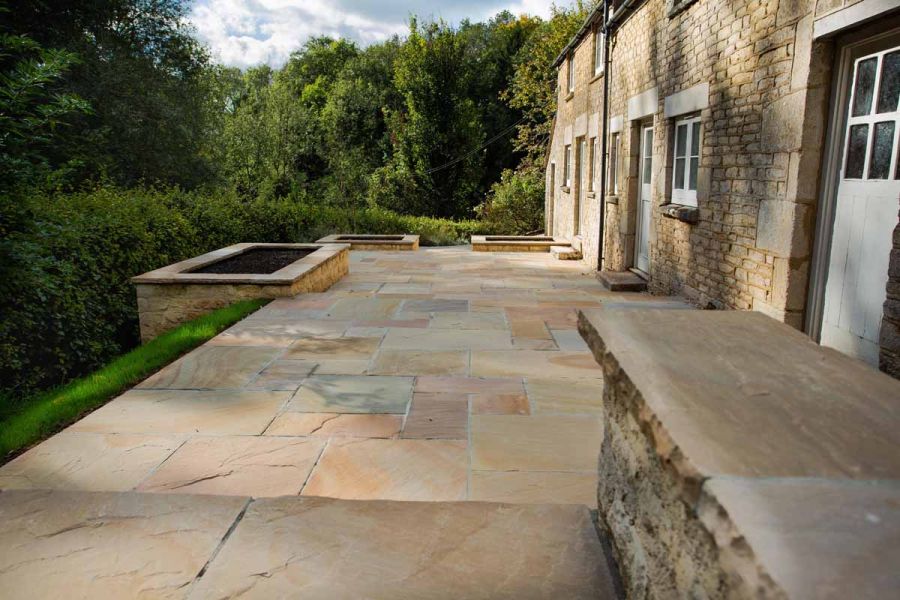 Step down to rear of rural stone-built cottage with Camel Dust sandstone patio running along length of building. 