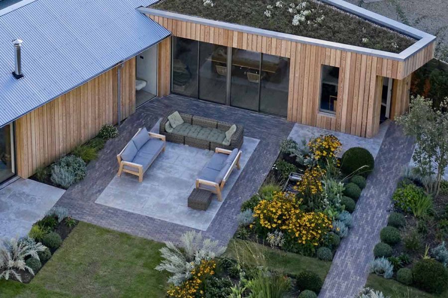 Overhead view of limestone patio framed with Stone Grey clay pavers in angle of wood-clad building with living roof.