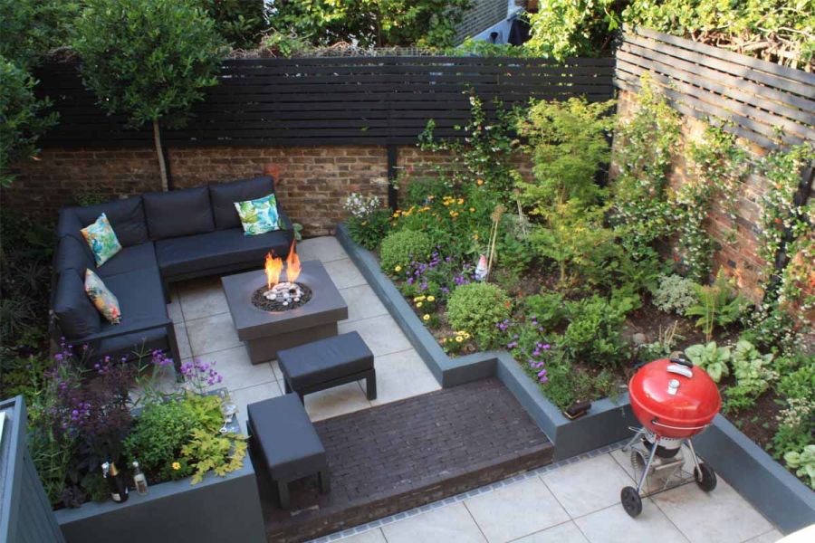 Low step with wide landing of Charcoal Grey brick pavers separates Silver Grey Porcelain paving between beds in walled back garden.