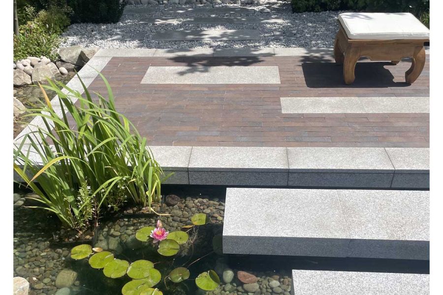 Chelsea Clay pavers and granite paved area floats above pond with lily pads at Gardeners World live 2022. Design by JKD Studio.
