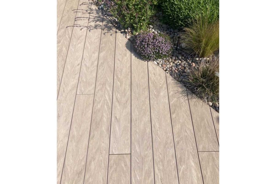 Cinnamon composite decking boards with ends cut to curve around planted bed with gravel mulch. Design by Nicholas Dexter.