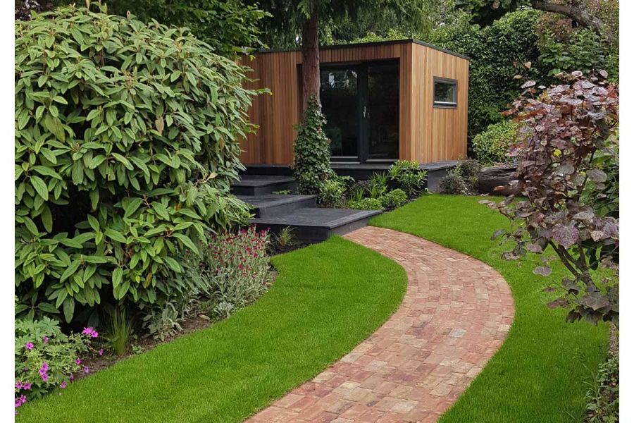 Cotswold Blend clay paver path curves through grass towards deep overlapping steps up through planted border to garden room.