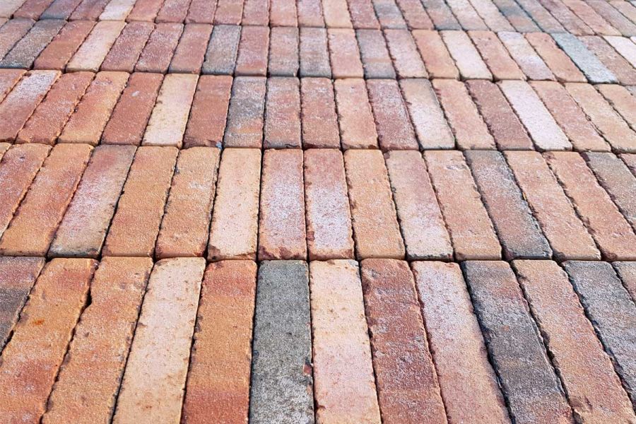 Close view across 5 courses of Bexhill clay pavers, laid stack bond, showing brown, red, black, buff and white colouring.