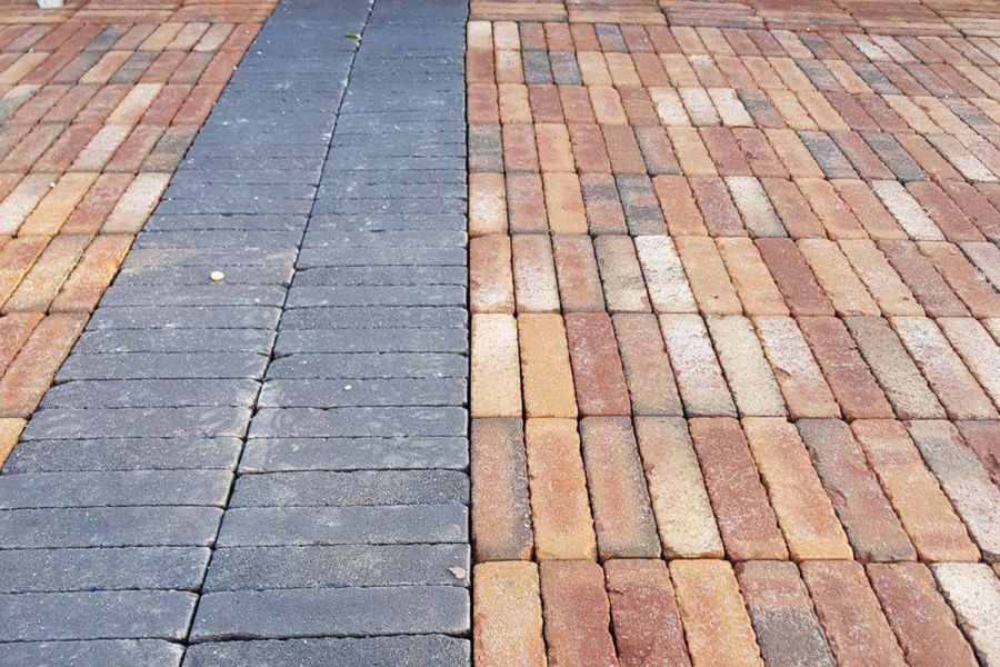 Close up shot of path of charcoal grey clay pavers running through Bexhill brick pavers in opposite patterns.