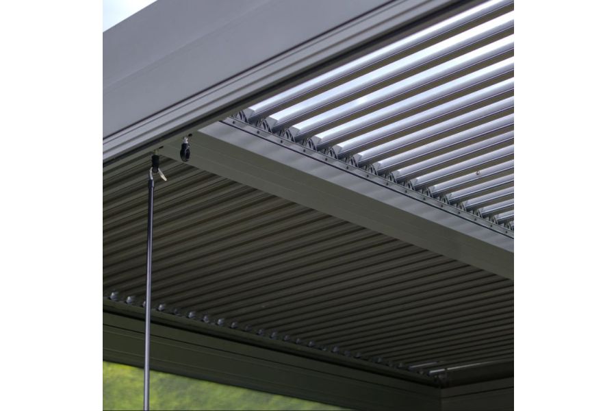 Hand crank dangles from hook in roof of Metal Pergola Dark Grey, with half of the louvres fully open, the others closed.
