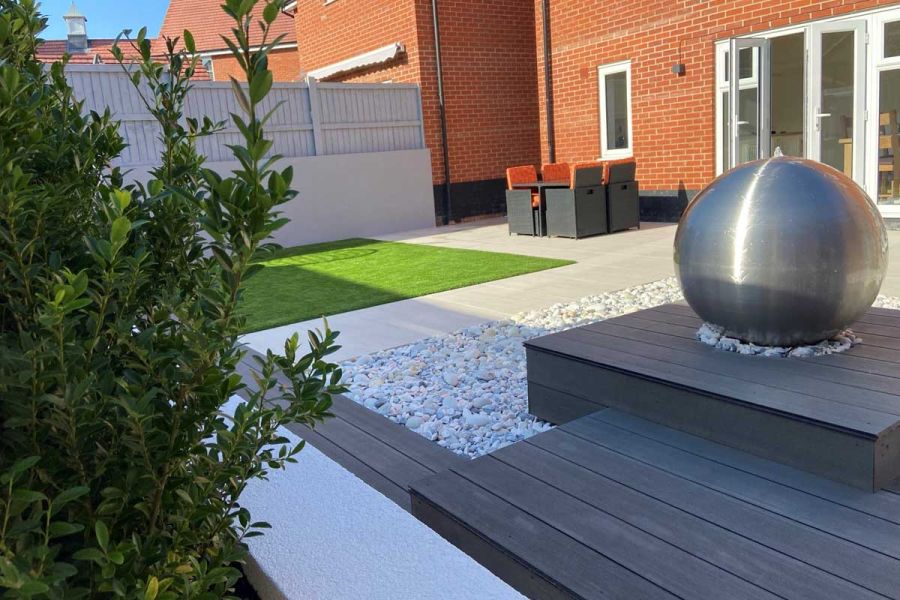 Steel ball water feature on plinth of DesignBoard Charcoal composite boards, set next to pebbled area. Design by Flitch Landscape.