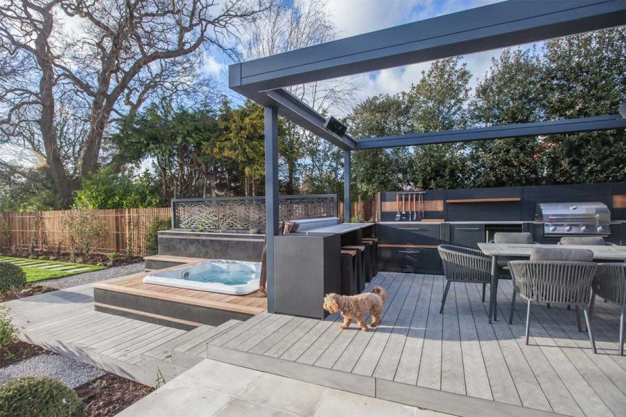 In long fenced garden, Luna DesignBoard descends from kitchen/dining area to hot tub set into contrasting composite decking boards.