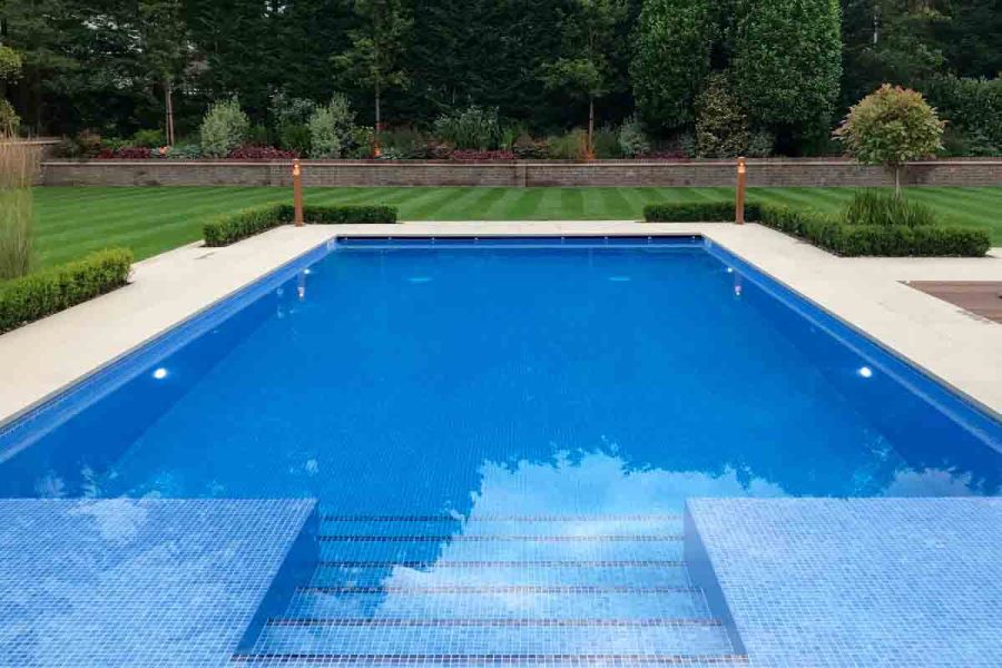 Blue tessellated tiles line rectangular swimming pool edged with Golden stone porcelain coping. By Landscape Design Studio.