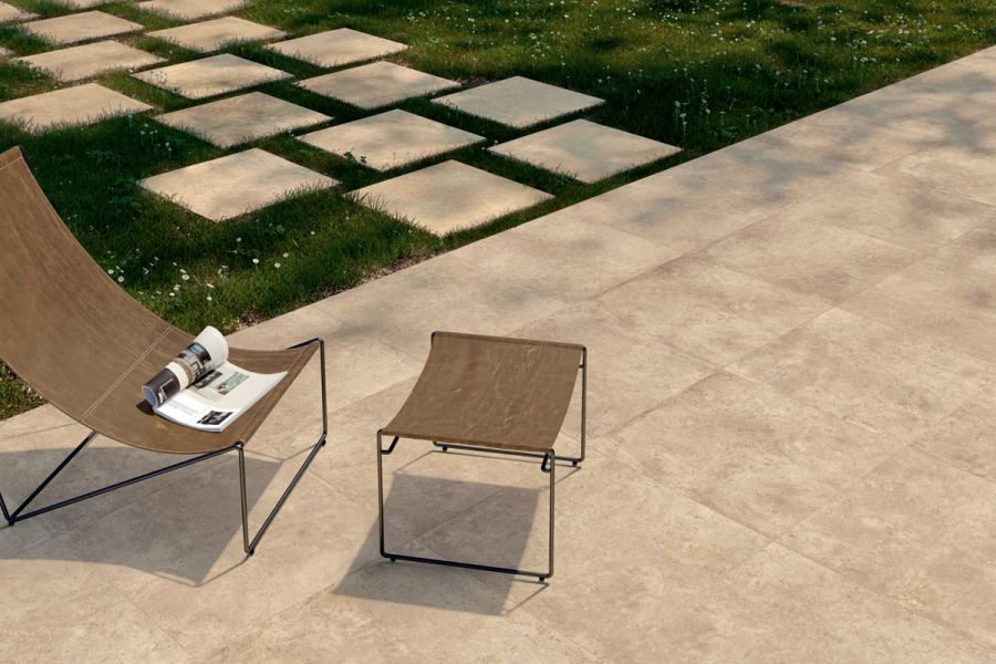 Deck chair and foot rest sitting on Corda 800x800 Large Paving Slabs and leading onto a lawn with Corda porcelain stepping stones.