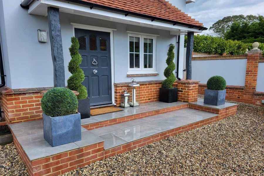 Wet Florence Storm Porcelain Paving alongside 20mm bullnose steps lead up to front door with topiary planting either side.