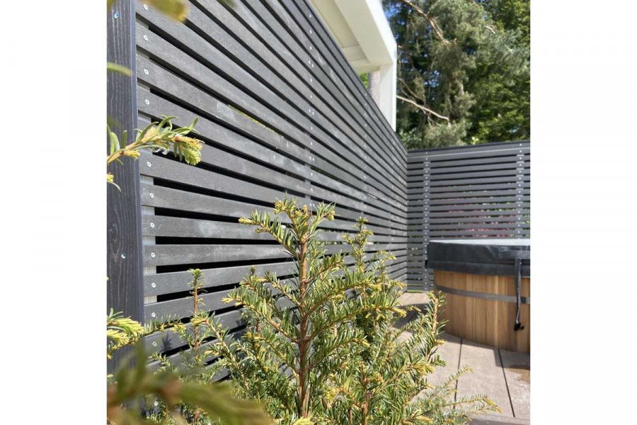 Dark Ash composite battens used for long, tall screen to edged boarded outdoor area with yew. Designed by Thouvenin Landscapes.