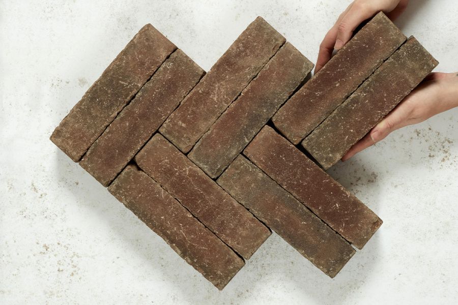 2 hands put 2 Derby clay bricks into double herringbone pattern formed by 8 pavers on white background. Free UK delivery available.