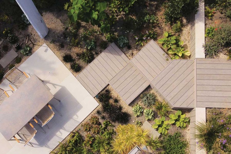 View down onto zigzag square steps in Traditional DesignBoard composite planks descending to paved patio with dining set.