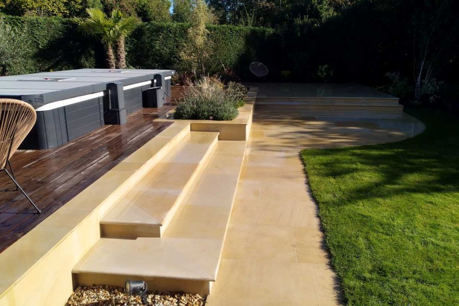 Curved corner patio below raised bed, with 2 steps to raised pool area, all built of Dune sawn sandstone by Duncan Ross.