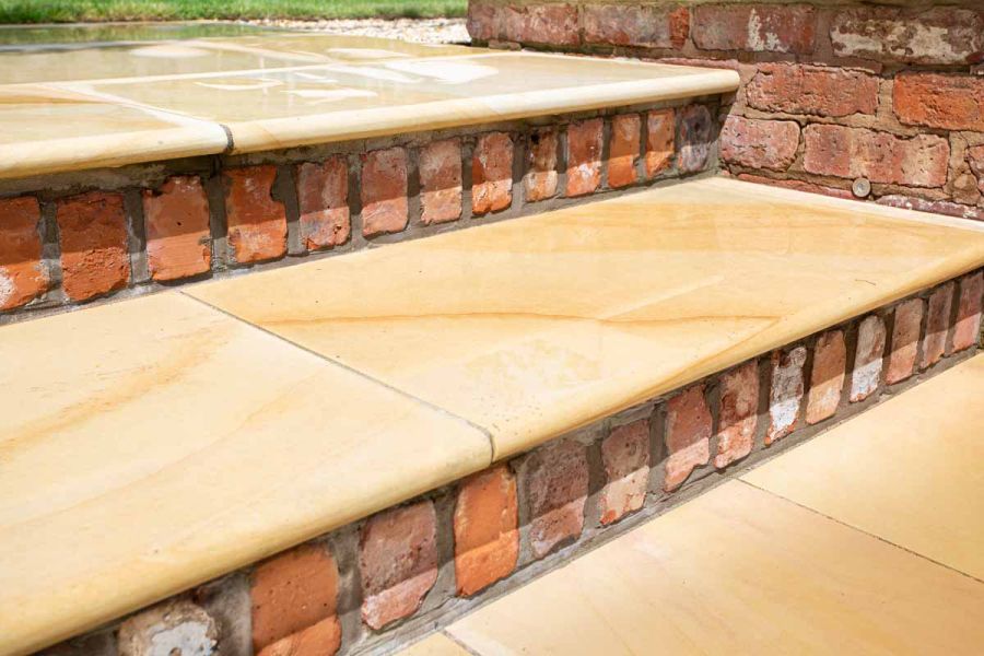 2 Dune Smooth sandstone bullnose garden steps with risers of brick headers, showing orange veining on slabs and flanking wall.
