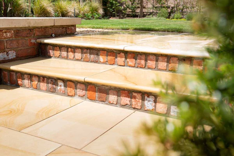 Close view of Dune sawn sandstone garden steps with bullnose edge profile, risers of brick headers, with matching paving below.
