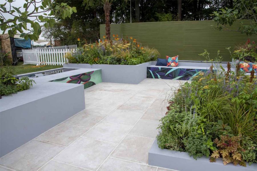 Egyptian Beige Limestone paving with rectilinear grey raised beds, green slatted fence and low leafy planting by Emma Tipping.