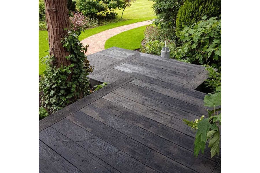 3 square platforms of Embered Millboard decking descend between tree and thick bushes to sinuous clay paver path set into grass.