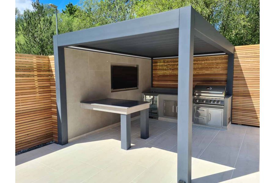 Metal Pergola Louvered Roof positioned over outdoor cooking area with bbq and fridge with DesignClad wall cladding featuring a tv.