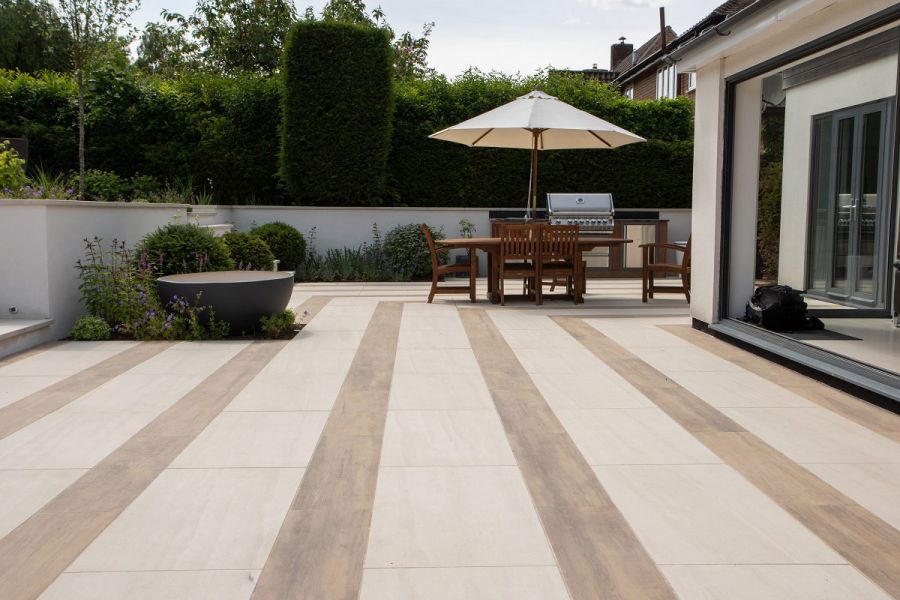 Modern house with bi-fold doors leading to large area paved with Faro porcelain paving and Rovere wood effect porcelain tiles.