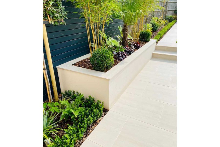 Faro Porcelain Paving path with 2 steps, next to mulched planted border and raised bed with bamboo. By Landscape Design Studio.