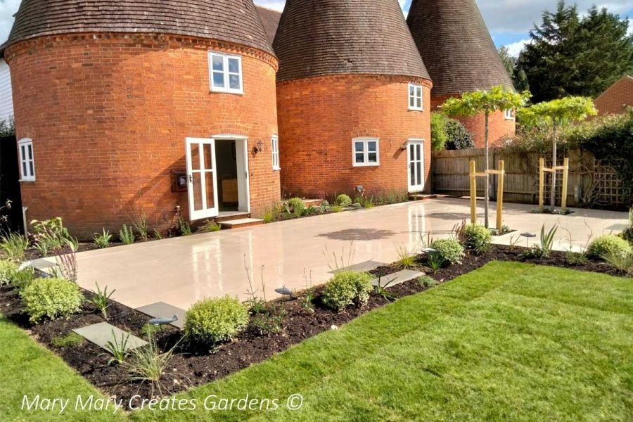 Florence Beige Outdoor Tiles UK laid as L-shaped patio backing onto 2 converted oast houses. Design by Mary Mary Creates Gardens.