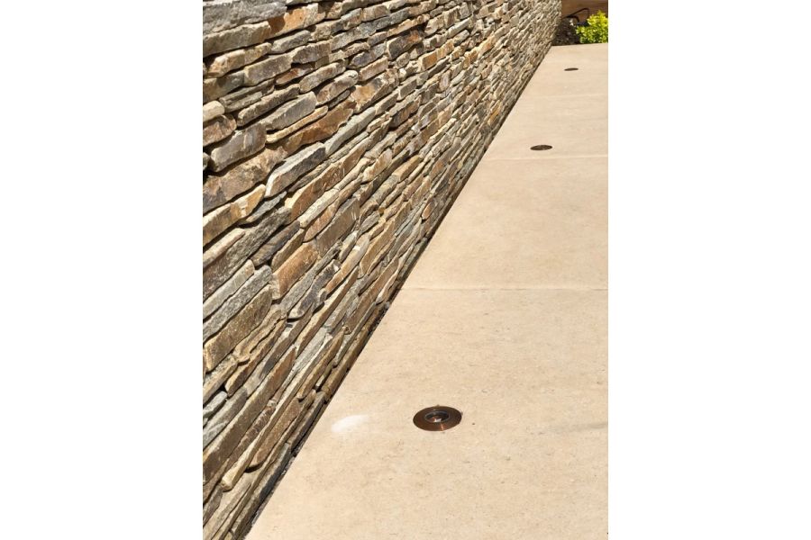 Close up of Florence beige porcelain outdoor tiles within set lights next to modern dry stone wall in design by Amanda Broughton.