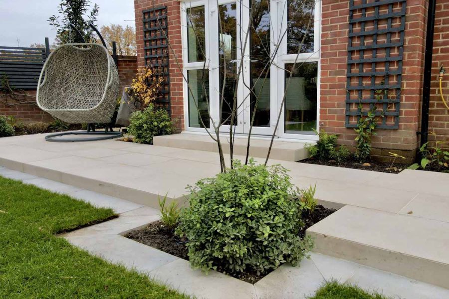 Florence Beige paving across back of house, with step up to french doors and step down to lawn with matching owing strip. 