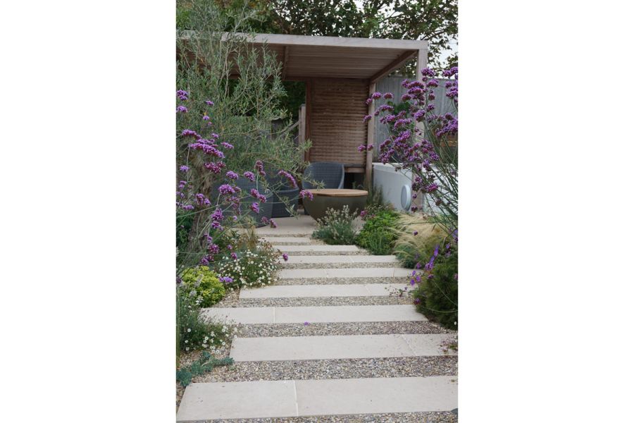 Staggered Florence Beige Porcelain paving planks set in gravel, lead between Verbena Bonariensis plants to covered seating area.