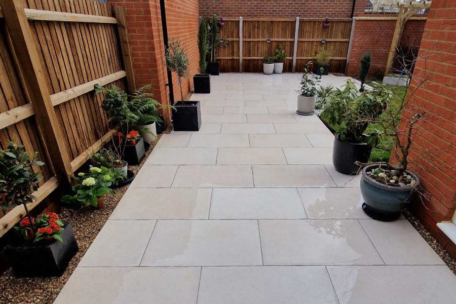 Functional patio in Florence Beige porcelain laid in a stretcher bond pattern and decorated with an assortment of planted pots.
