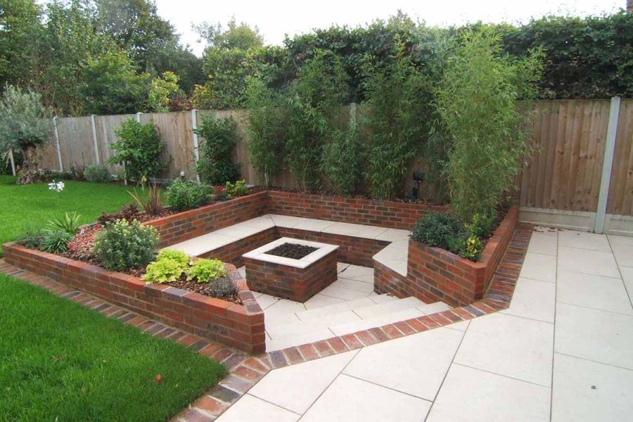 Brick-sided sunken seating area. Florence Beige porcelain steps descend to benches and firepit topped with matching paving slabs.