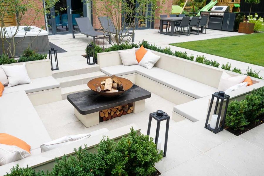 Florence Grey Porcelain Paving used around sunken seating area surrounded by planted copings, fire-pit in the middle.