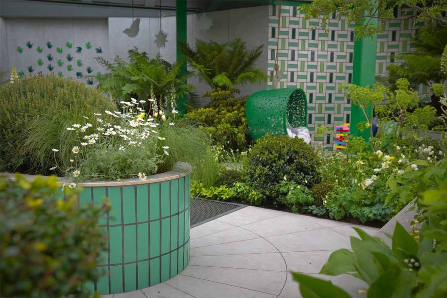 Radius-cut Florence Grey porcelain paving marries with curve of green-tiled raised bed in RHS Chelsea design by Kate Gould Gardens.